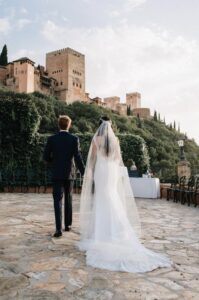 Novios celebrando su boda frente a los jardines y arquitectura de la Alhambra de Granada, con detalles andaluces y vistas monumentales