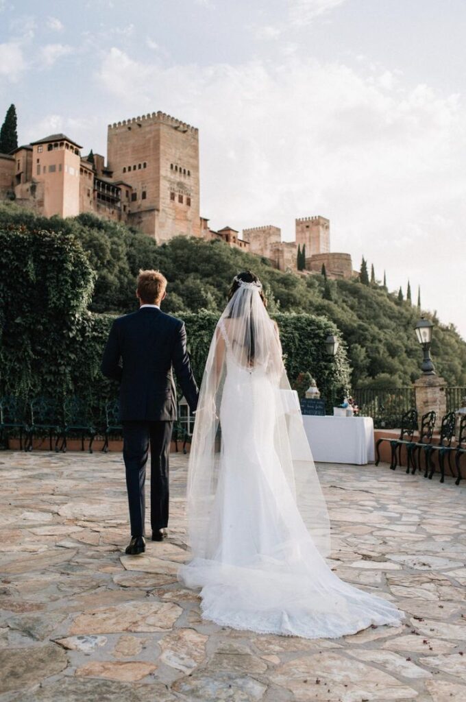 Novios celebrando su boda frente a los jardines y arquitectura de la Alhambra de Granada, con detalles andaluces y vistas monumentales