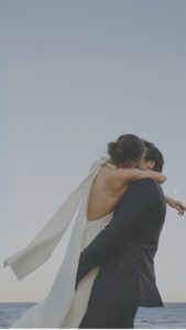 Pareja de recién casados se besa con ternura mientras se abrazan, capturando un momento íntimo y romántico de su boda
