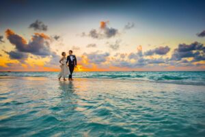 Pareja joven celebrando una boda romántica en la playa al atardecer